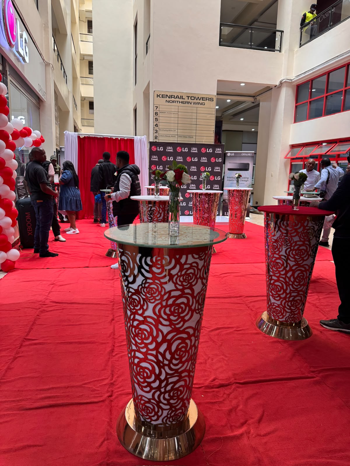 Branded pedestal display tables with rose-patterned wraps at an LG product launch activation