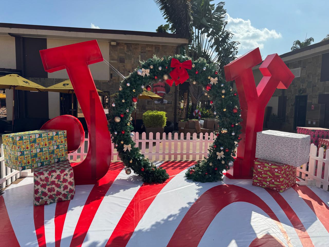 Oversized JOY letter installation with a decorated wreath archway and wrapped gift boxes at a Nairobi shopping centre