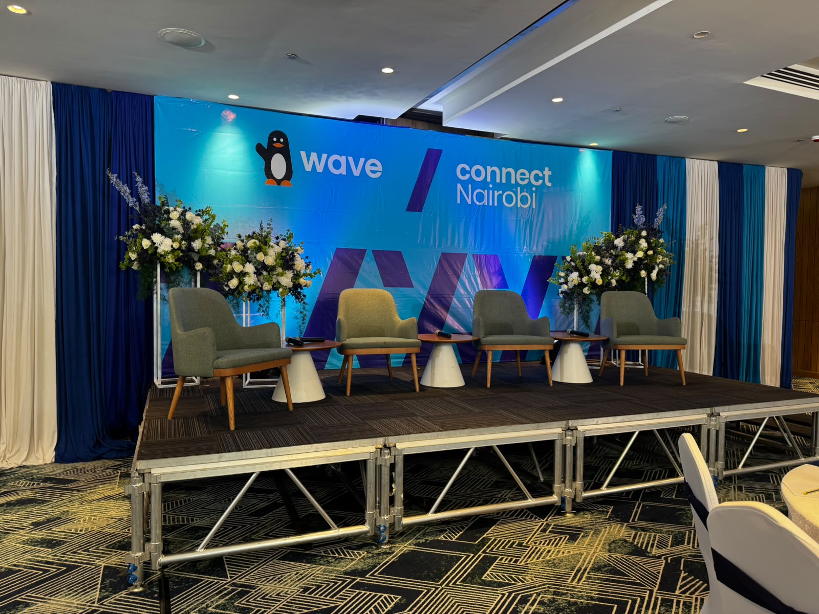 Corporate conference stage setup with branded backdrop and floral arrangements
